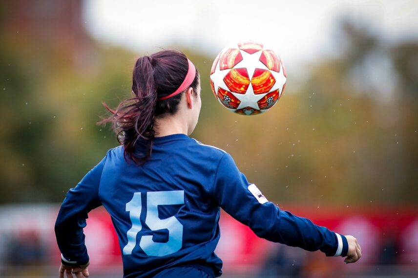 A woman in athletic gear skillfully plays soccer, maneuvering the ball on the field.