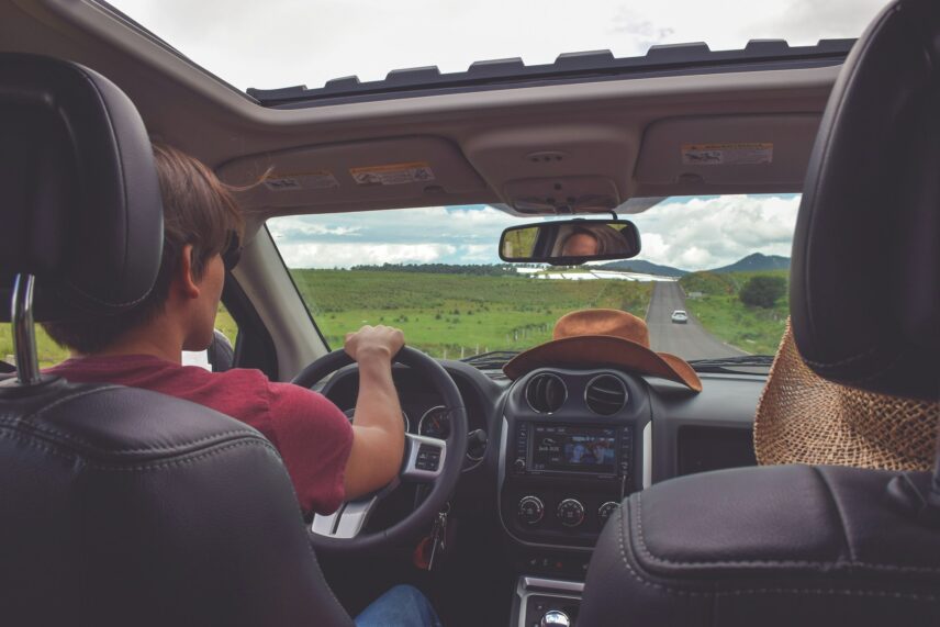 An image of a driver taken from the backseat perspective of a vehicle