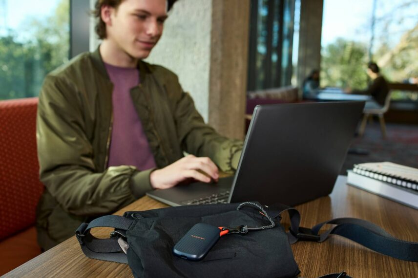 Young man using a laptop with a portable storage device on a table