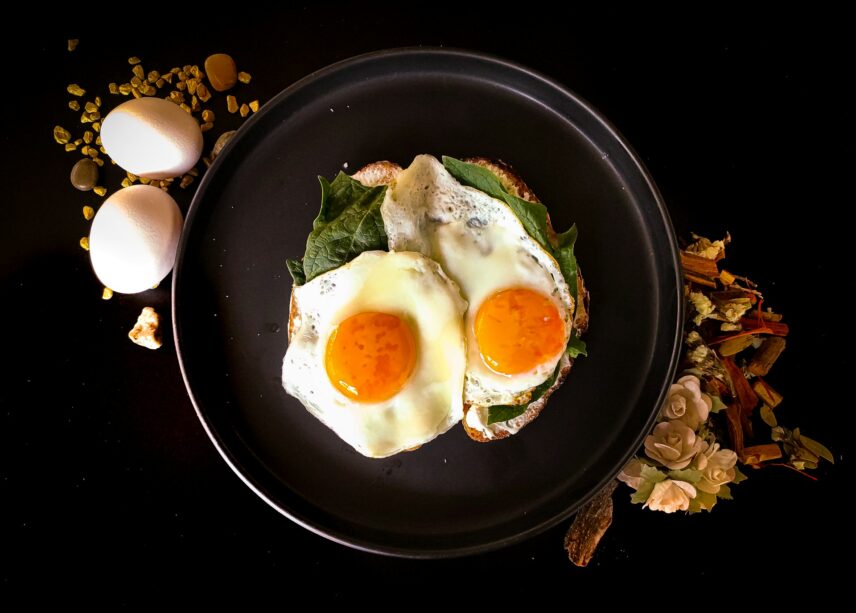 Two eggs on a plate, surrounded by fresh spinach and herbs, creating a vibrant and healthy meal presentation.