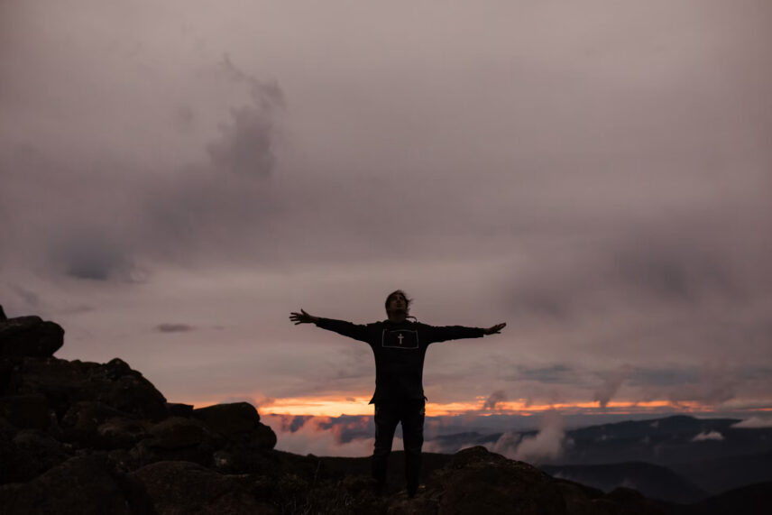 man stretching arms out over wide open expanse
