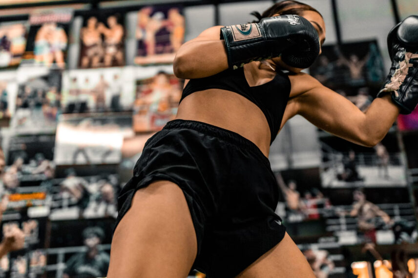 female boxer in black with posters behind her