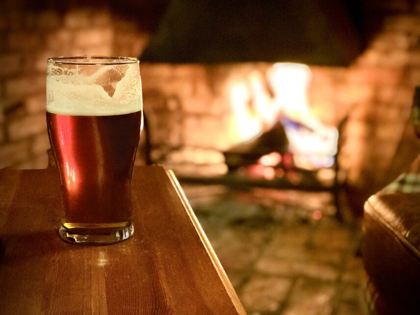 Dark brown beer on wood table in front of fireplace