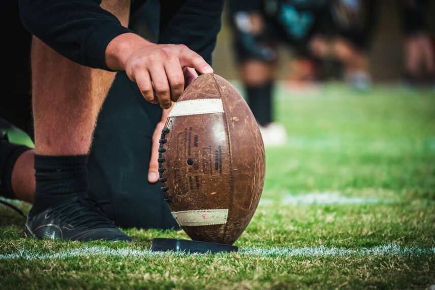 Man holding a football on a tee
