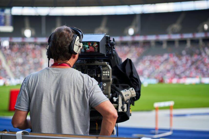 Man operating a camera at a sports game