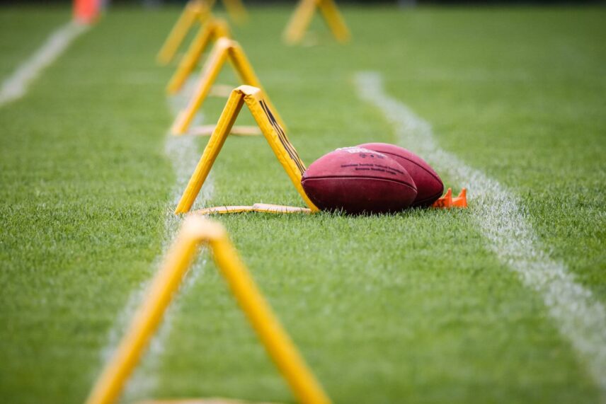 Yellow training equipment and two footballs on the grass