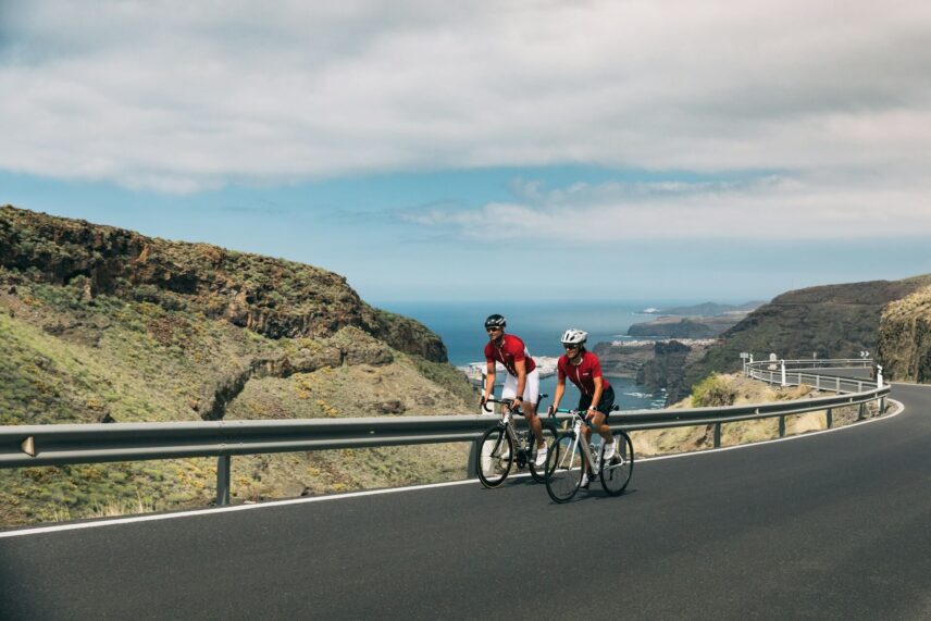 two people riding touring bikes against a coastal backdrop