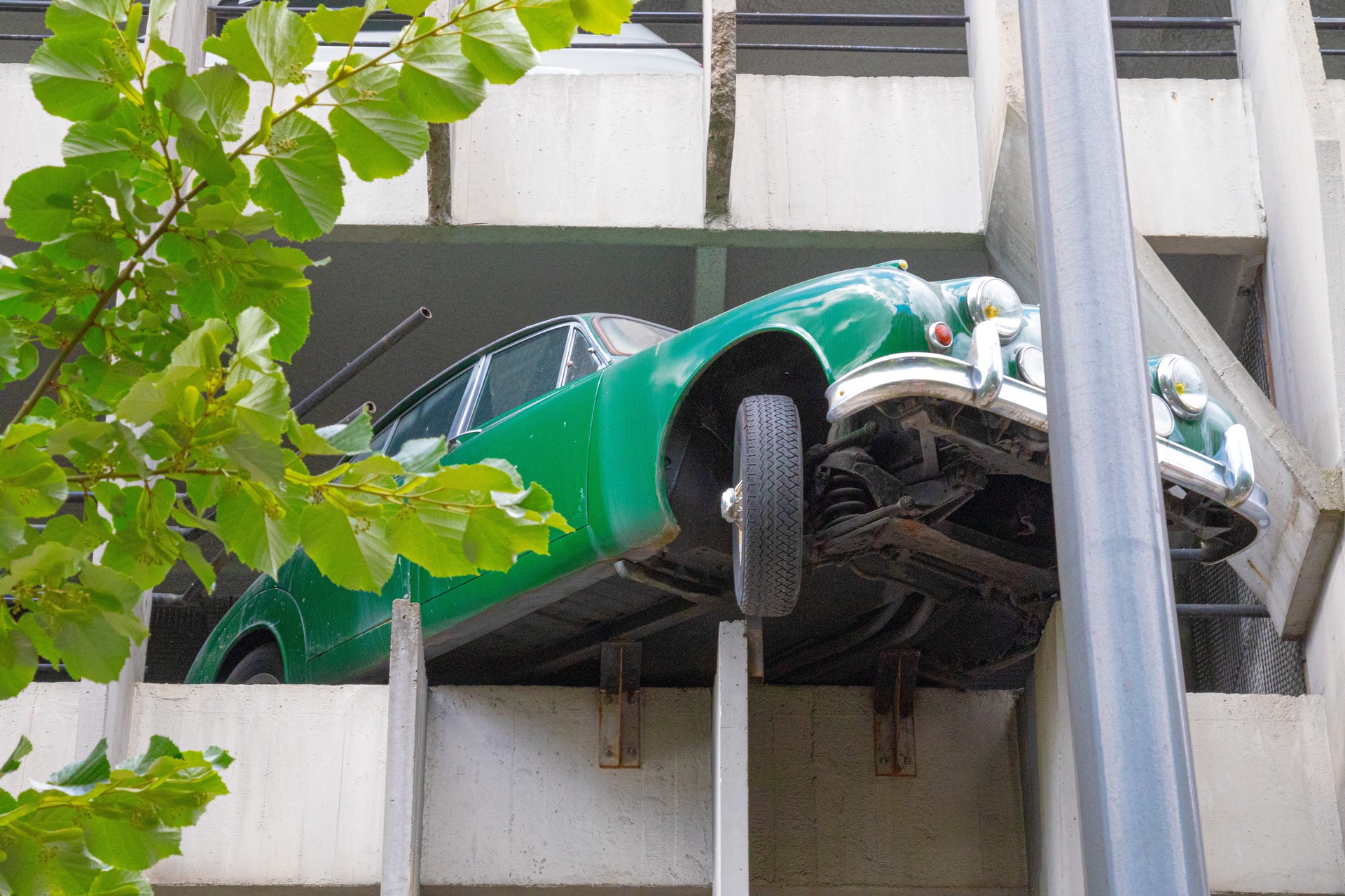 weird green car parked sticking out of a building