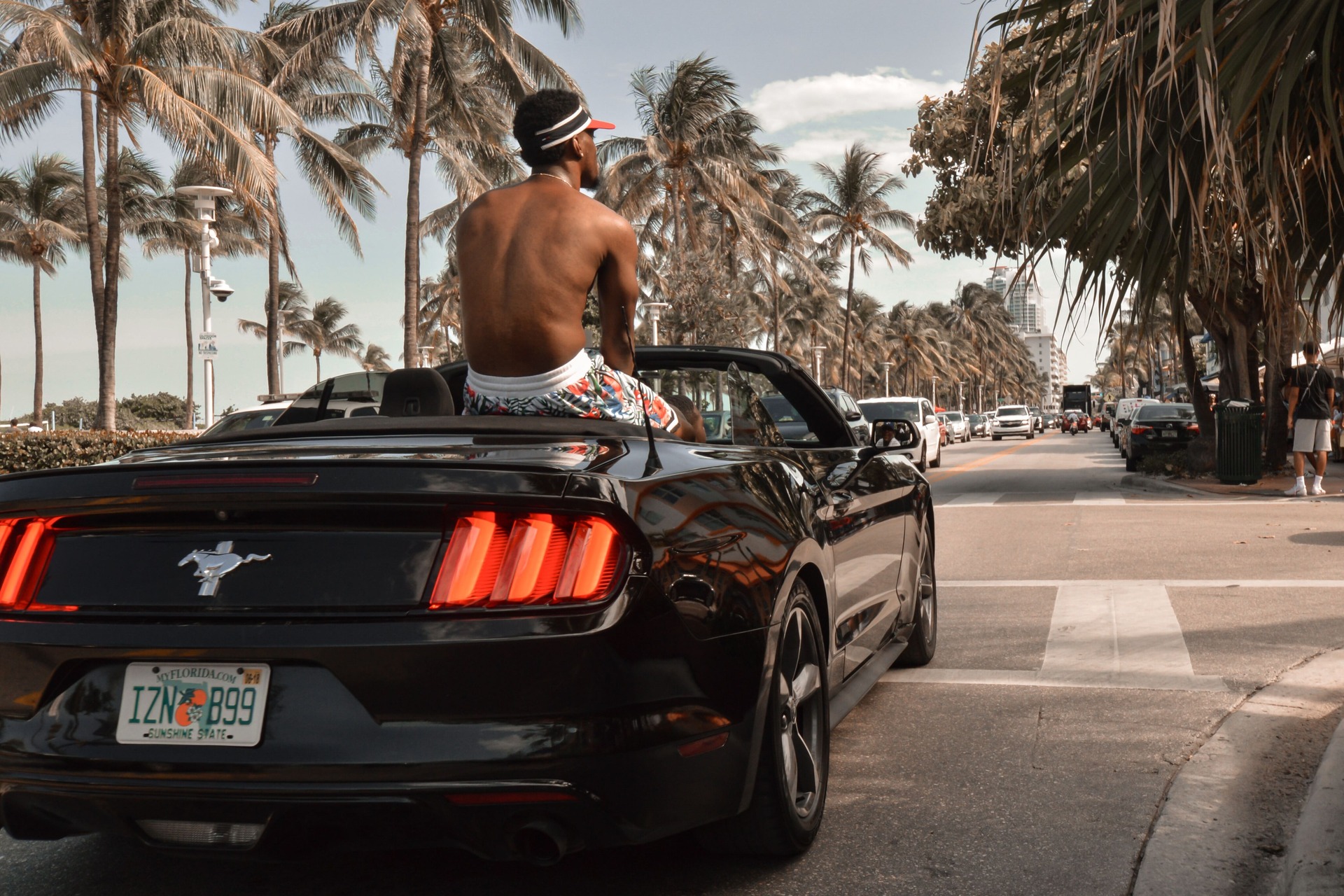 A shirtless man riding on the back of a car in Florida