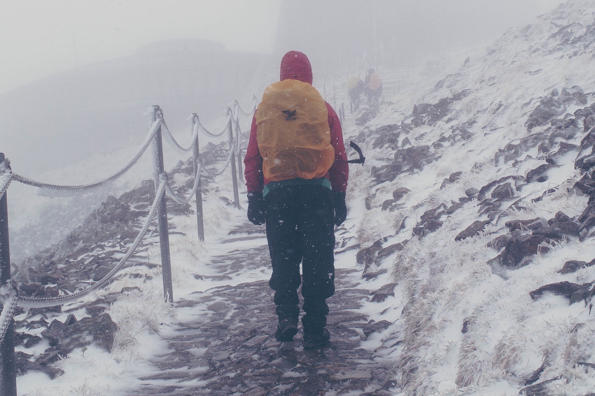 Man climbing a snowy winter mountain path