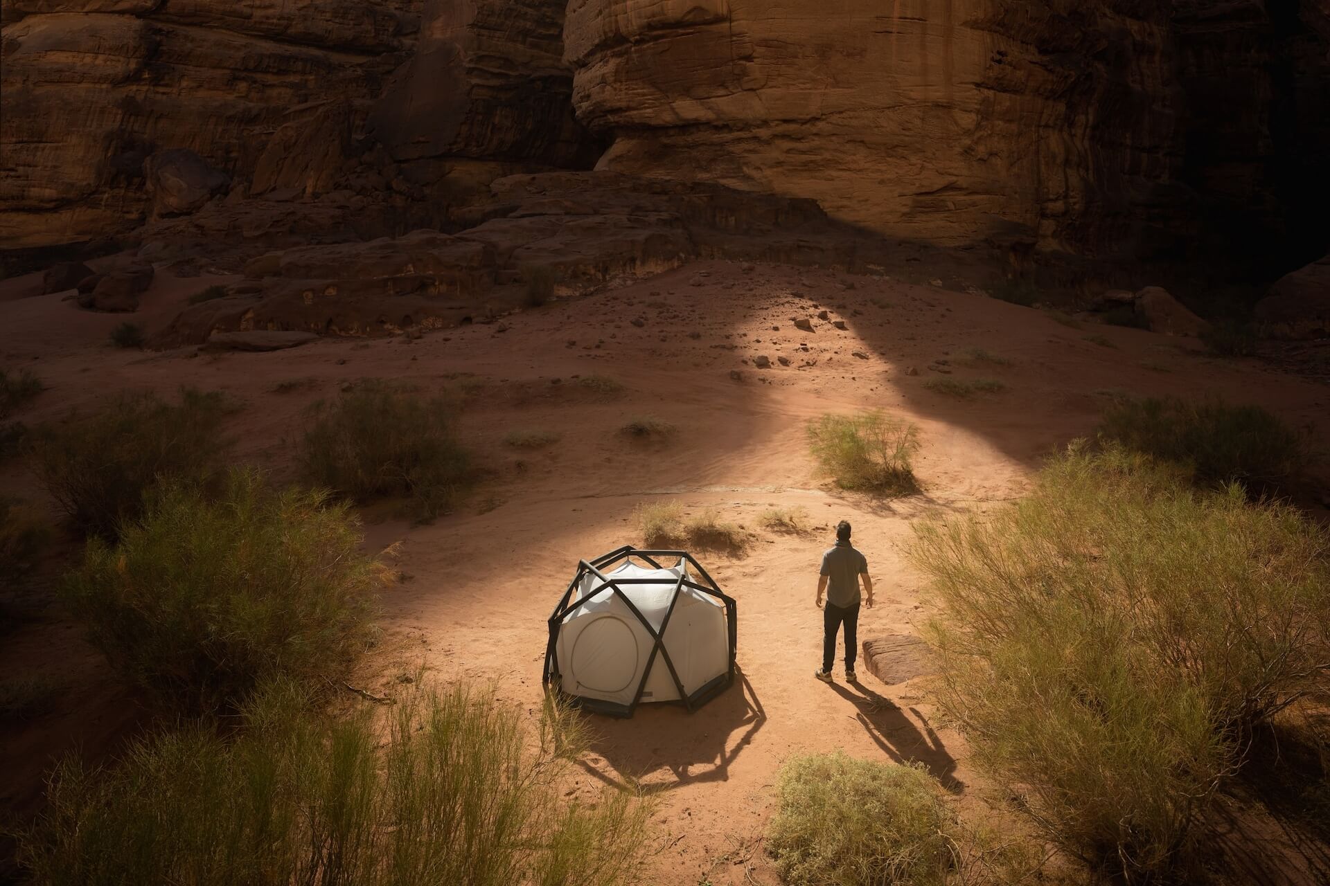 Man standing next to a tent in the desert