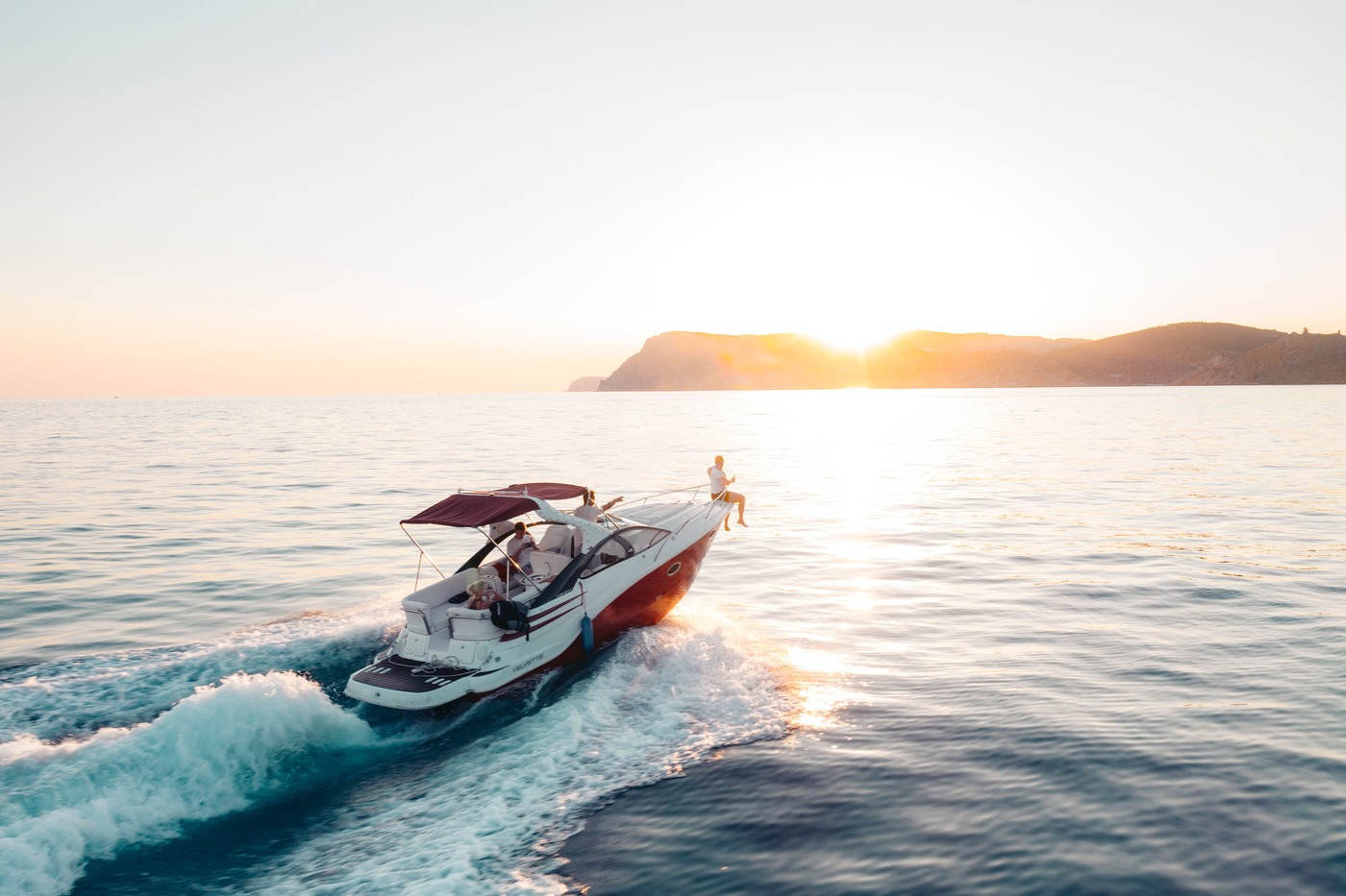 A speedboat riding toward sunset