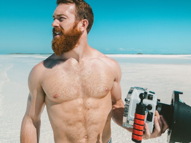 Muscular man, shirtless on beach.