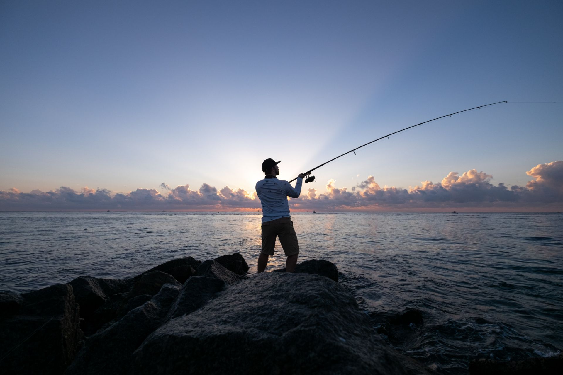 Man with fishing rod on the rocks.