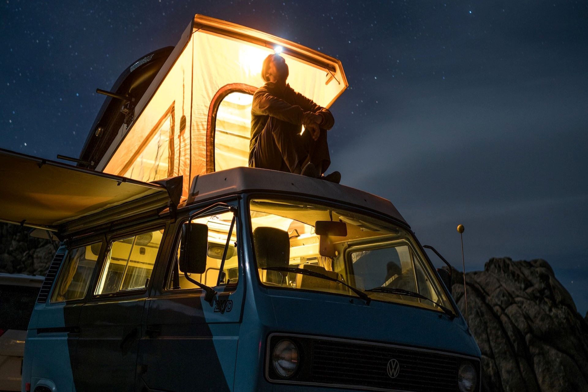 Man enjoys the night sky with the best van-to-camper conversion ideas.