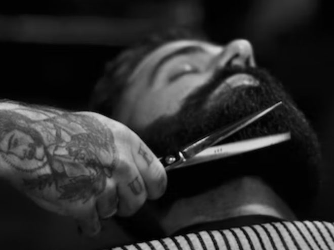 Man lying back, getting his beard trimmed.