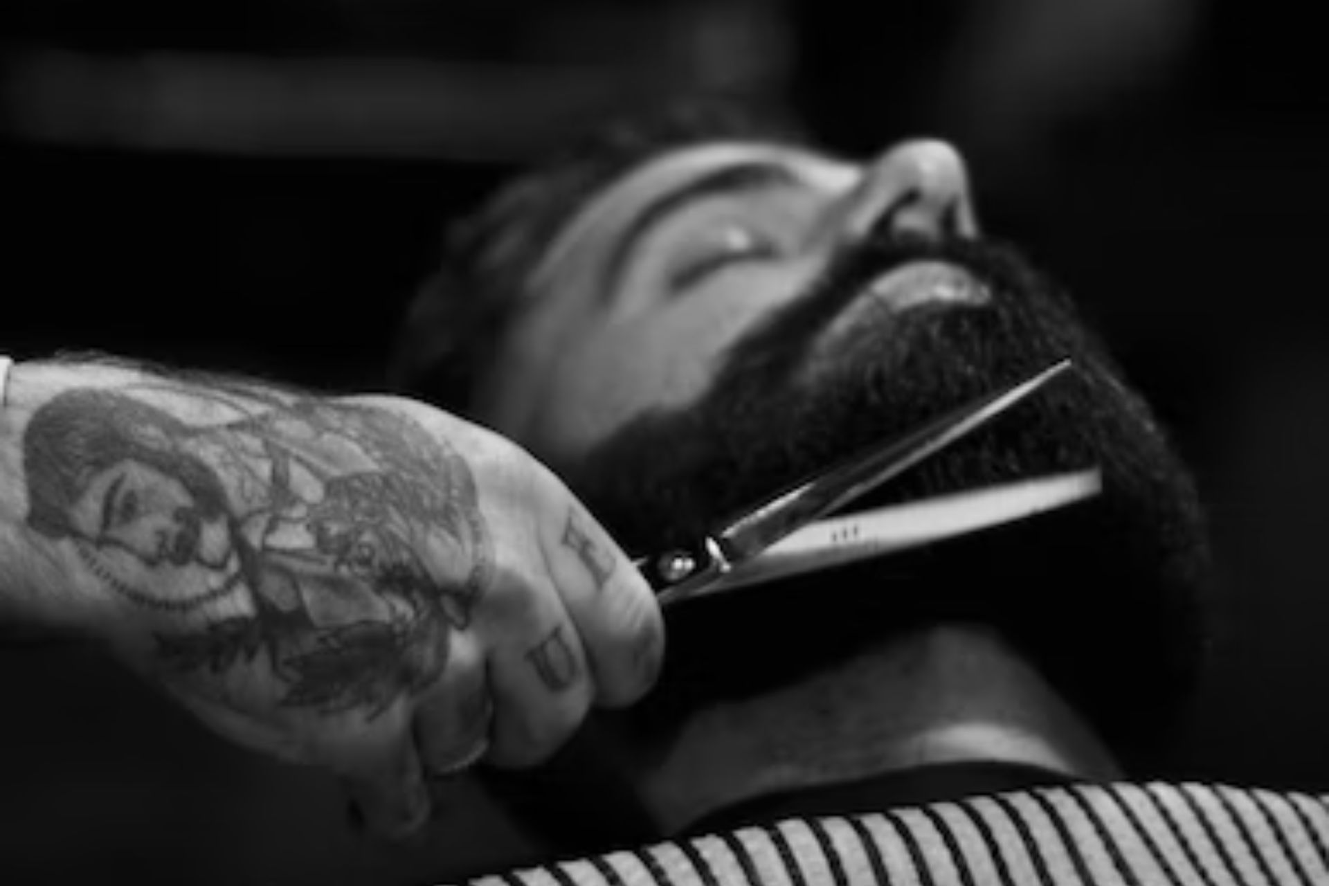 Man lying back, getting his beard trimmed.