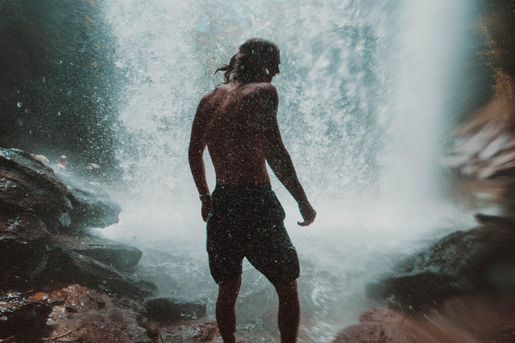 Ripped man under a waterfall.