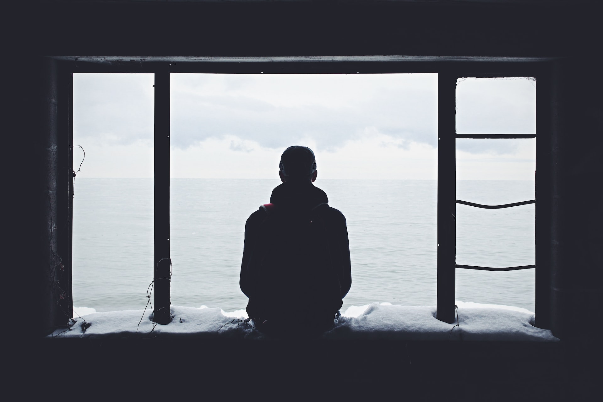 Man standing in front of a window with clouds outside.