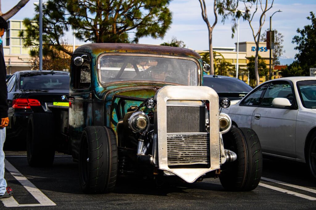 A rust-covered rat rod sitting in a parking space.