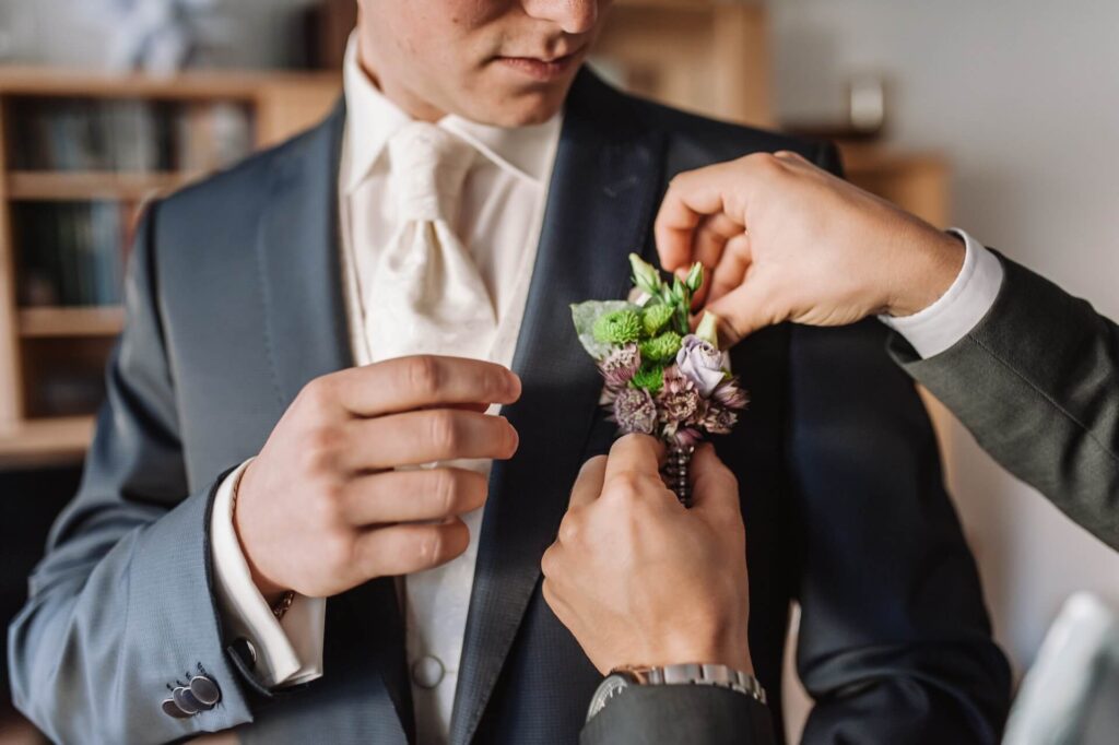 A man adding accessories to his outfit - semi formal attire men wedding