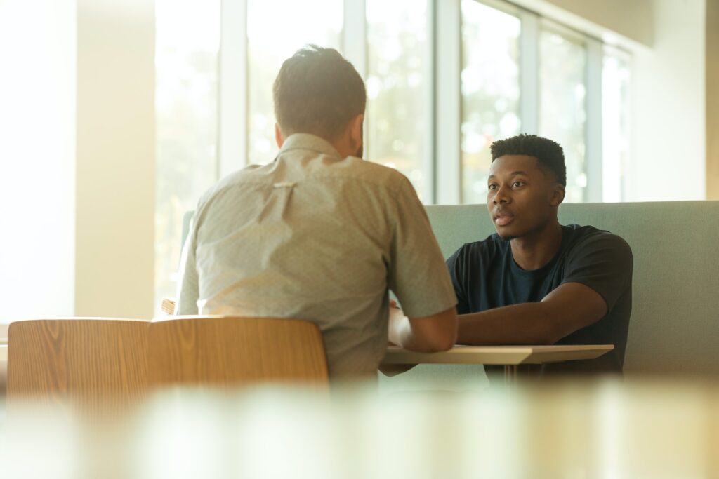 Two men sitting at a table mid-conversation