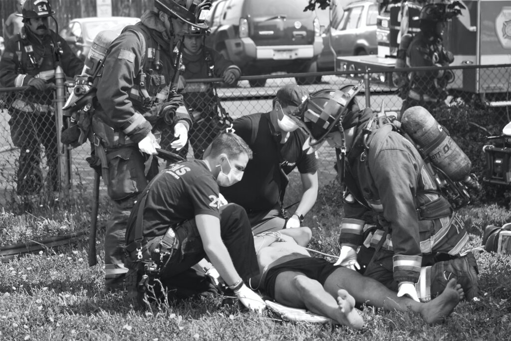 A group of firefighters and first responders attend to an unconscious person.