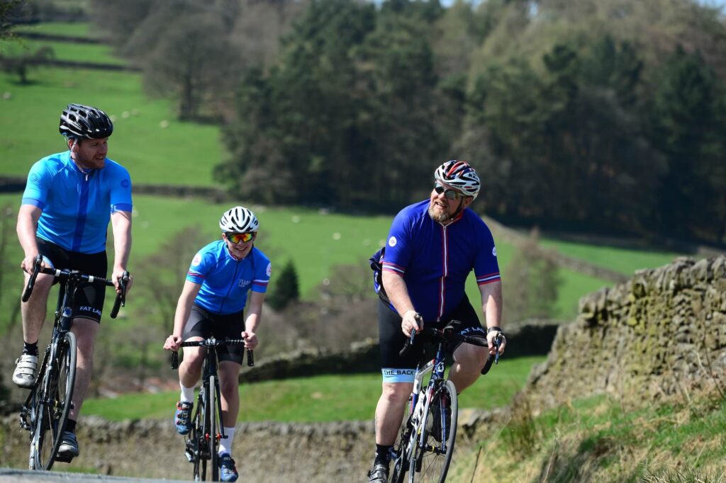 Three guys ride bicycles in the countryside.