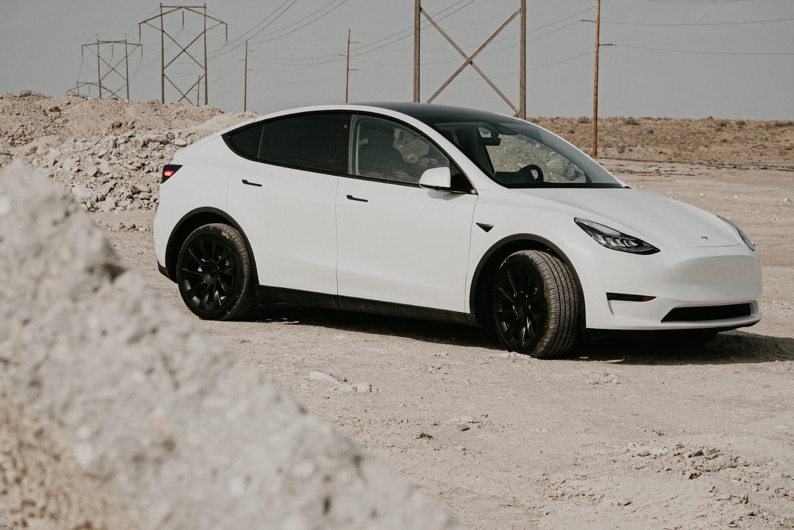 White Tesla Model Y drives on white sand.
