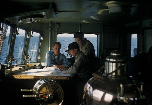 Marines inside boat looking at research documents. 