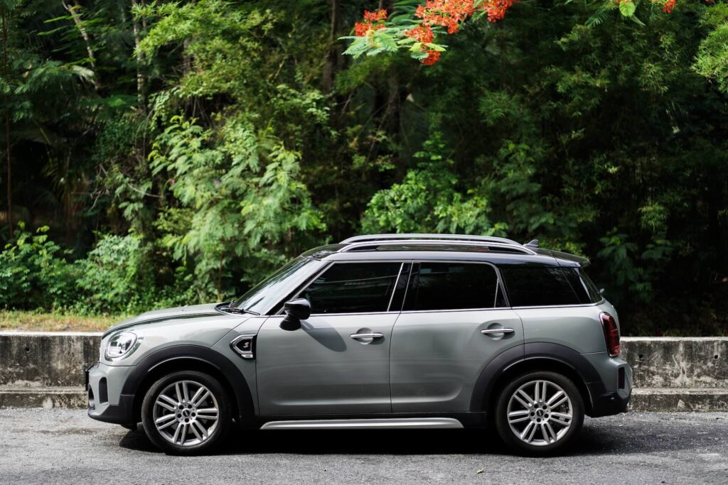 Silver Mini Countryman parked on the road overlooking a forest. 