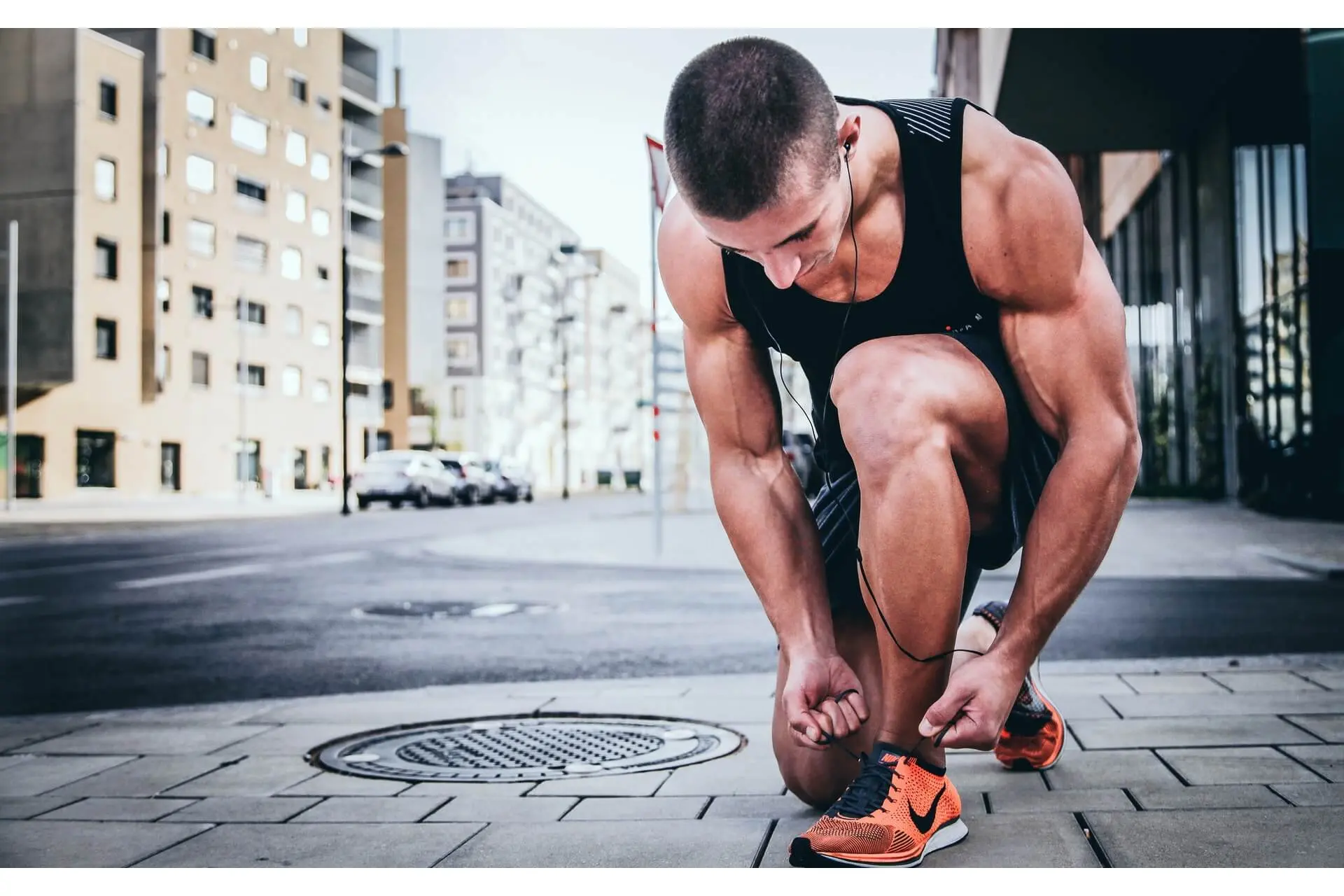 alexander-redl-d3bYmnZ0ank-unsplash (1) A man on his knees tying his shoes