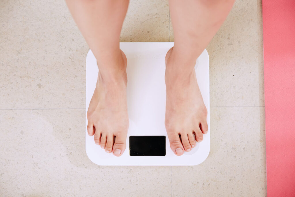 Person stands on a scale to measure their weight. 