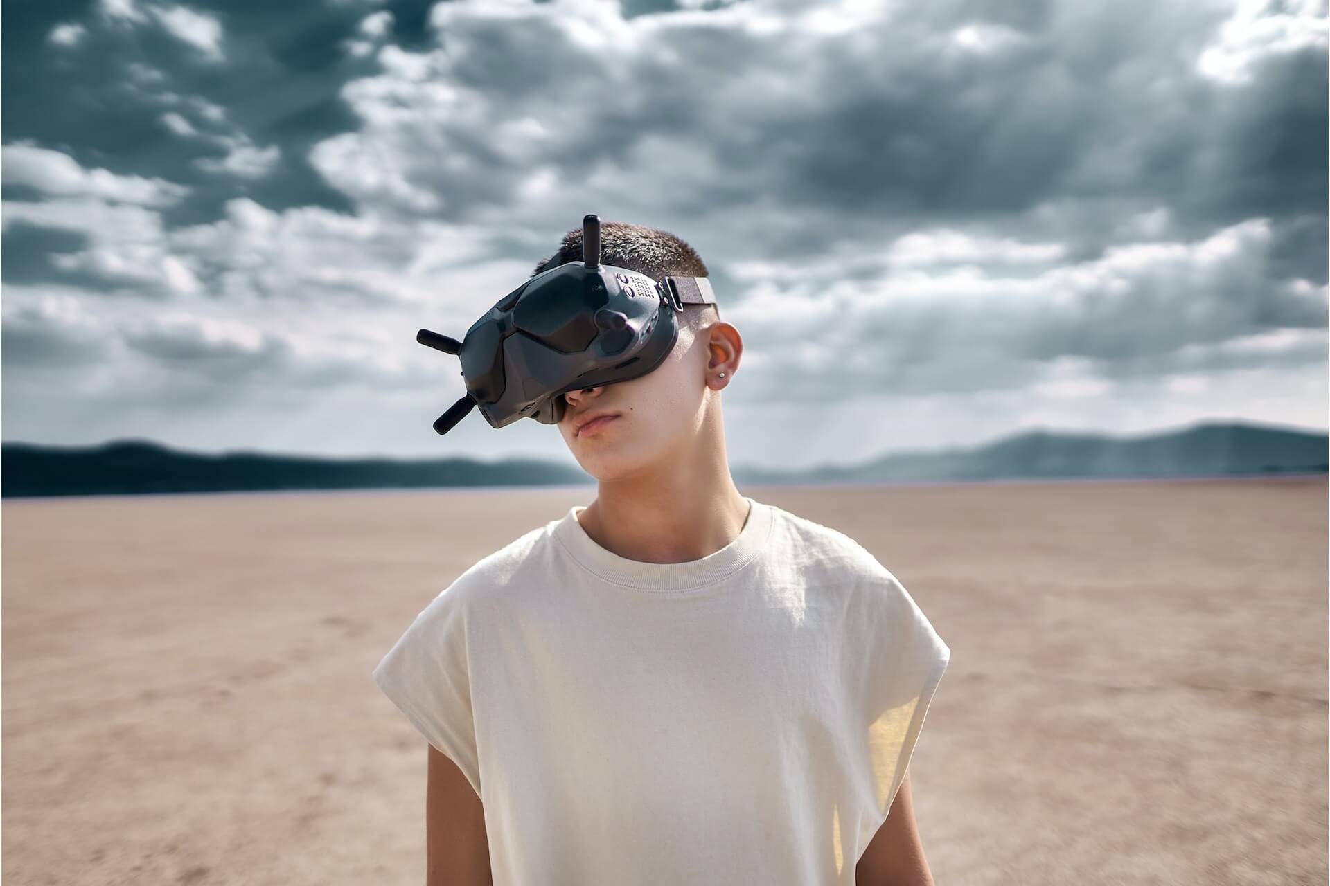 Man in a white vest with Virtual reality goggles standing in a dessert