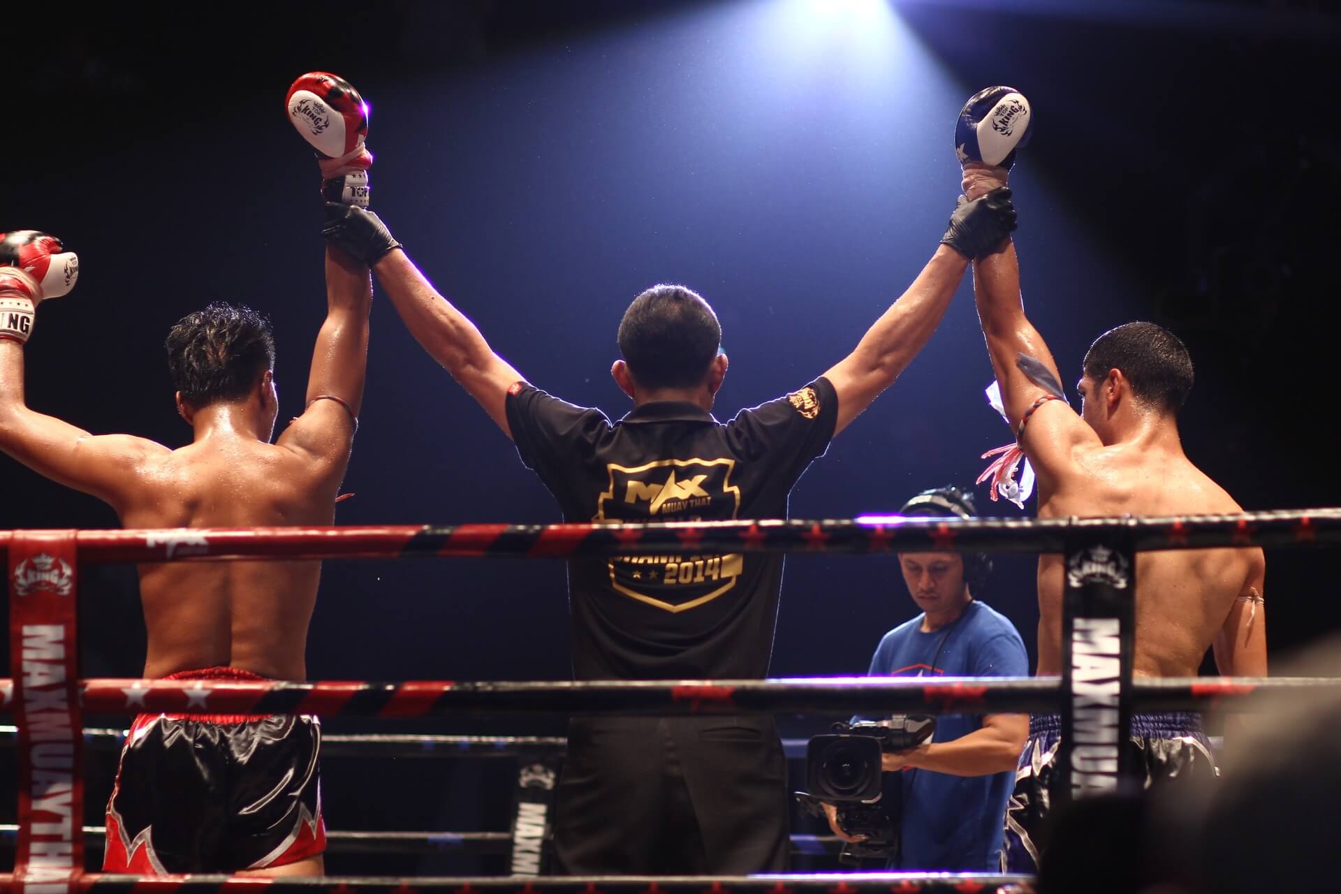 Muay Thai referee raising the hands of both fighters