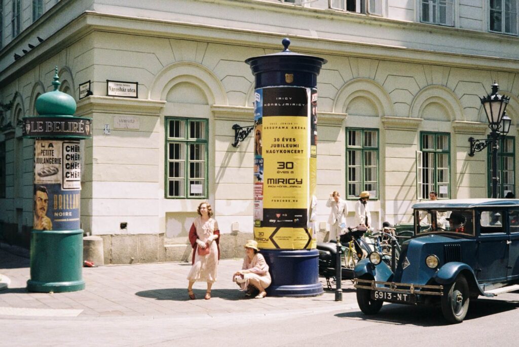 Vintage city with two women standing by a pillar and a vintage truck driving past 