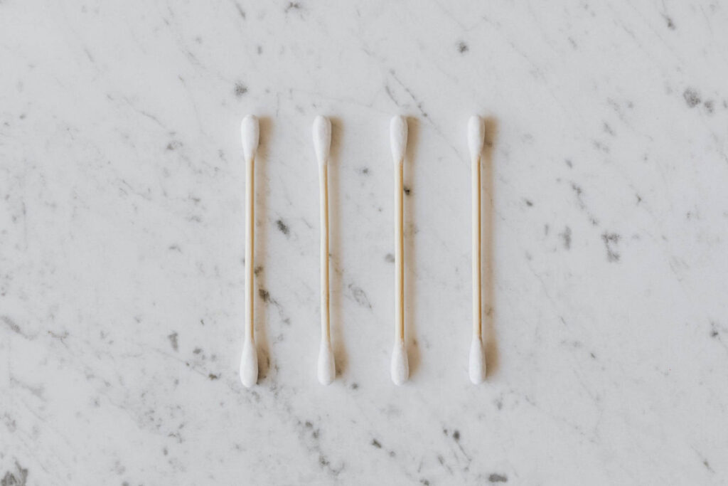 Four q-tips in a row on a marble background