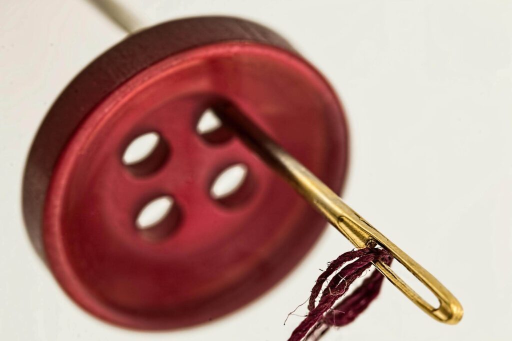 big red button with a gold needle thread