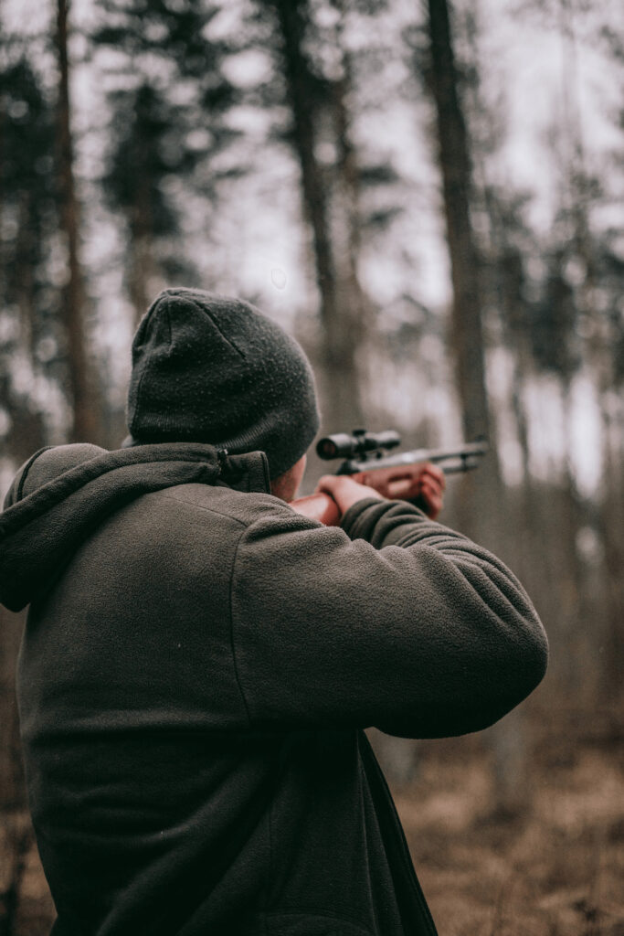 A hunter aiming through a rifle. 