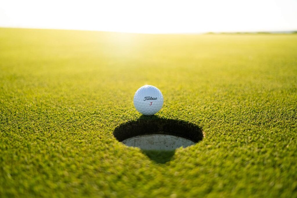 Golf ball on the edge of the hole on a golf course.