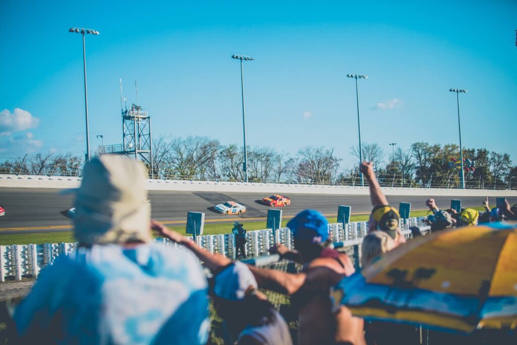 Fans watch as stock cars zoom around the Daytona International Speedway.