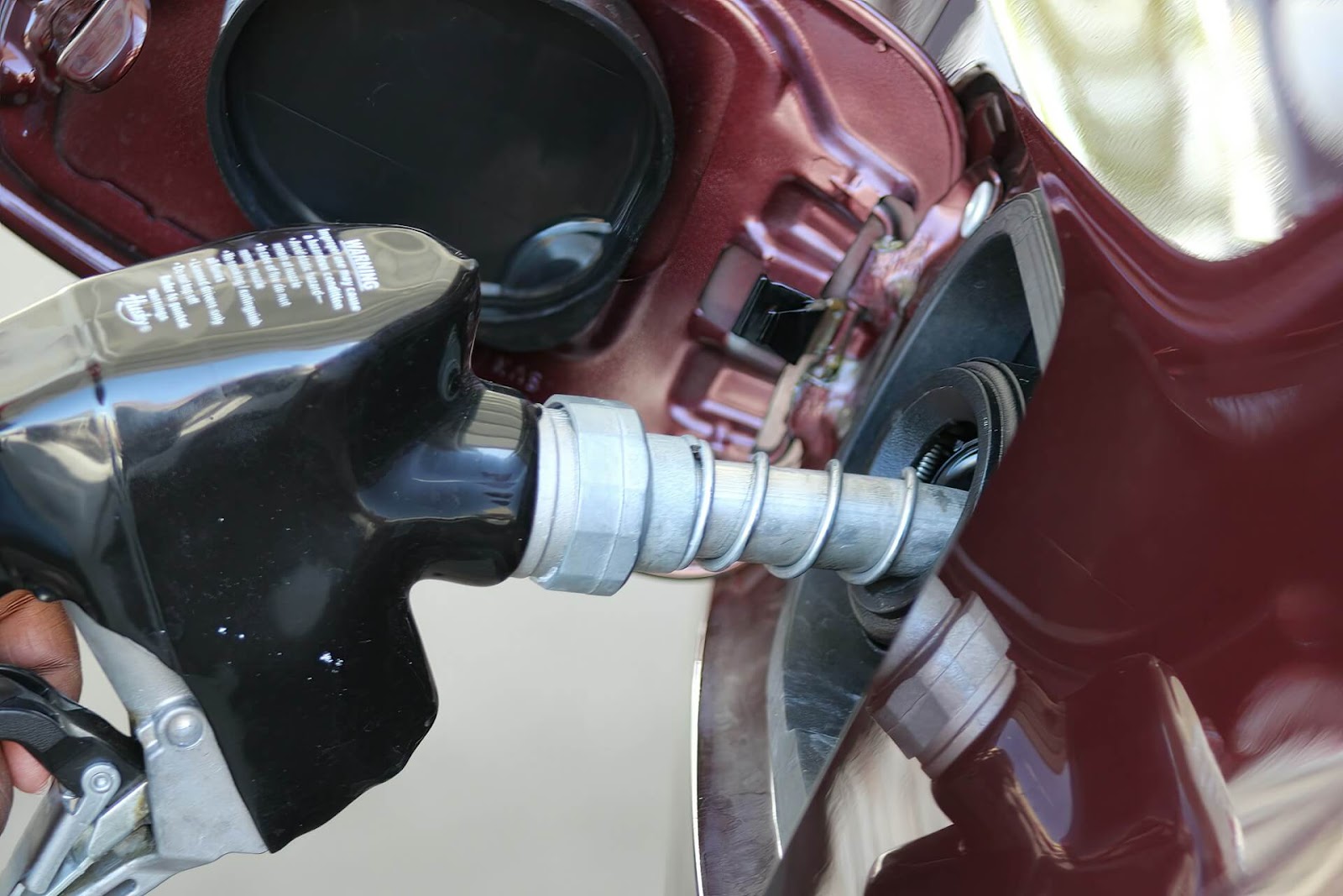 Black gasoline pump refueling a red car