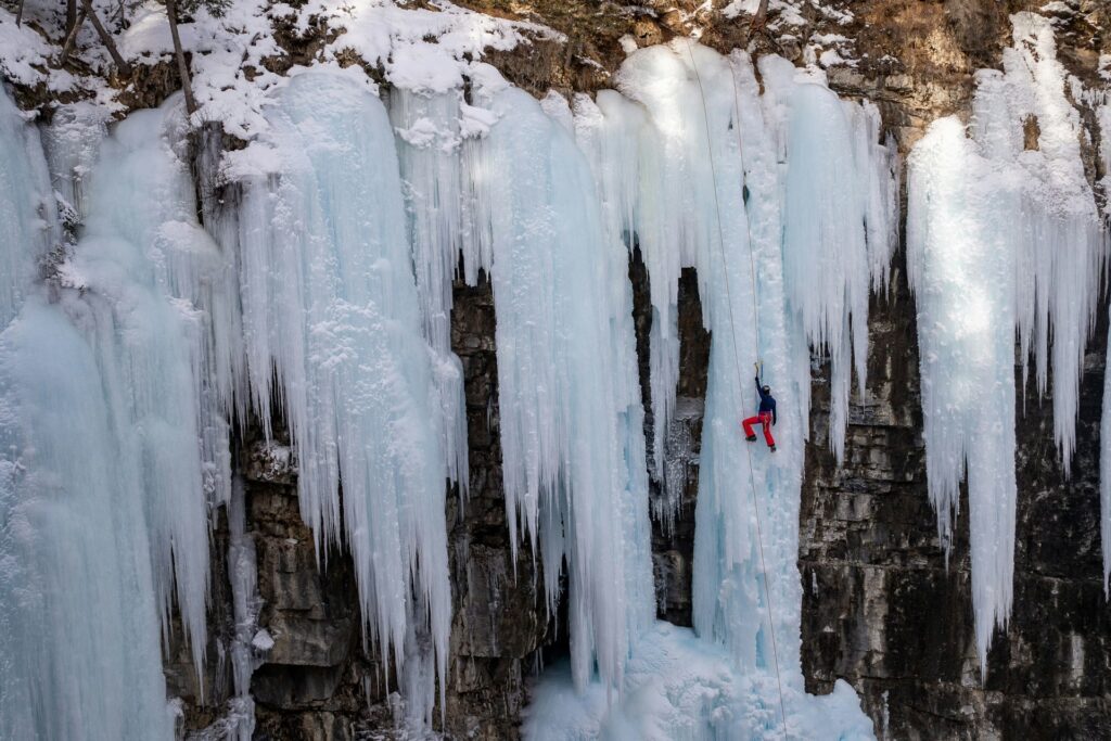 Person scaling a frozen waterfall