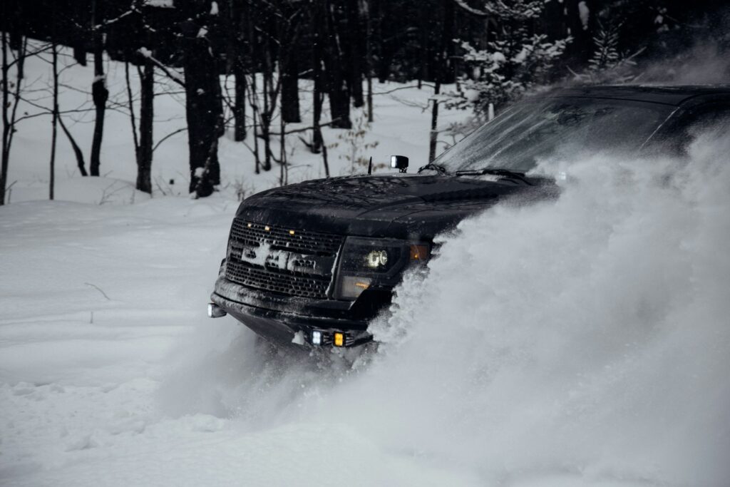 a Ford truck pushing through heavy snow
