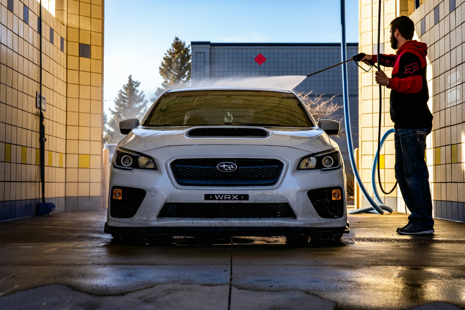 A WRX being hosed down by a car wash employee