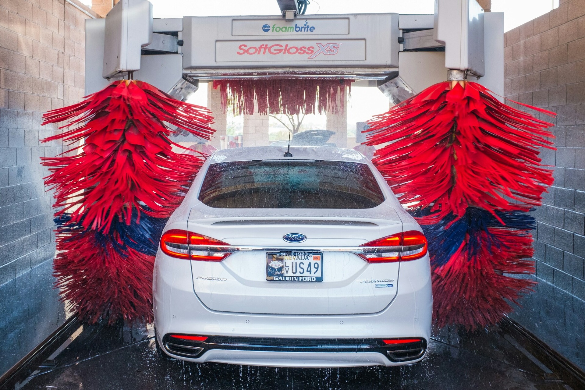 A white Ford Fusion going through a car wash