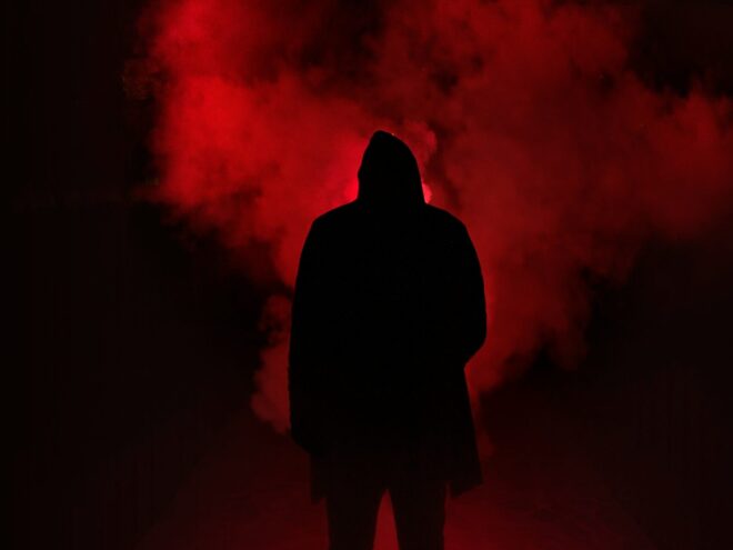 shadow of a man standing in front of red smoke.