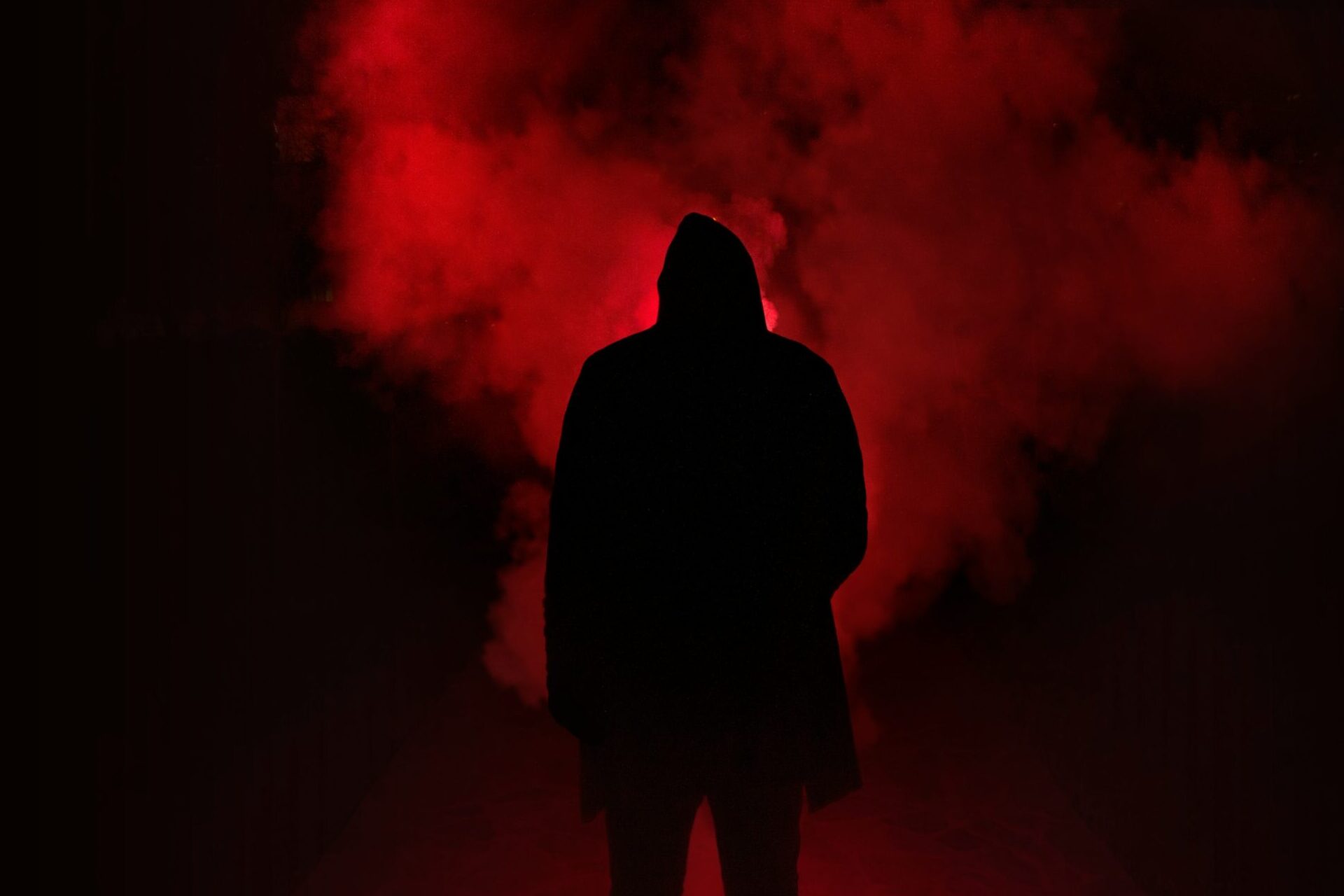 shadow of a man standing in front of red smoke.
