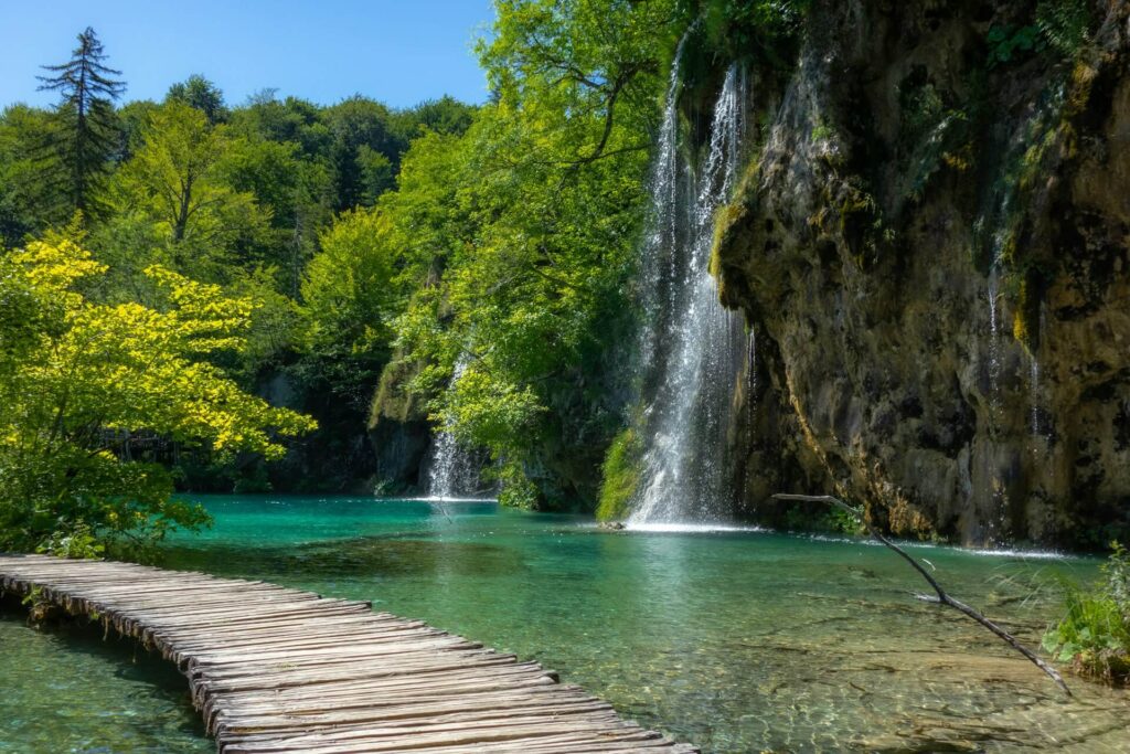Brown wooden dock leading to waterfalls at Plitviče Lakes National park.