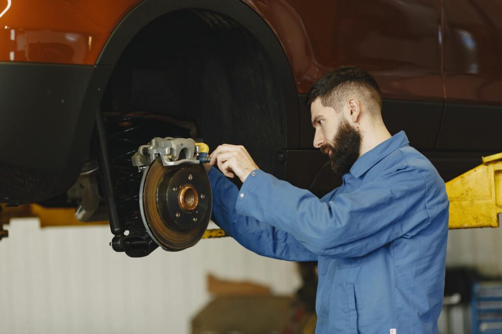 A mechanic working on a lifted car's brake pad